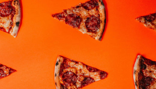  Pizza slices on vibrant orange background representing balanced approach to nutrition and metabolism without restriction or guilt